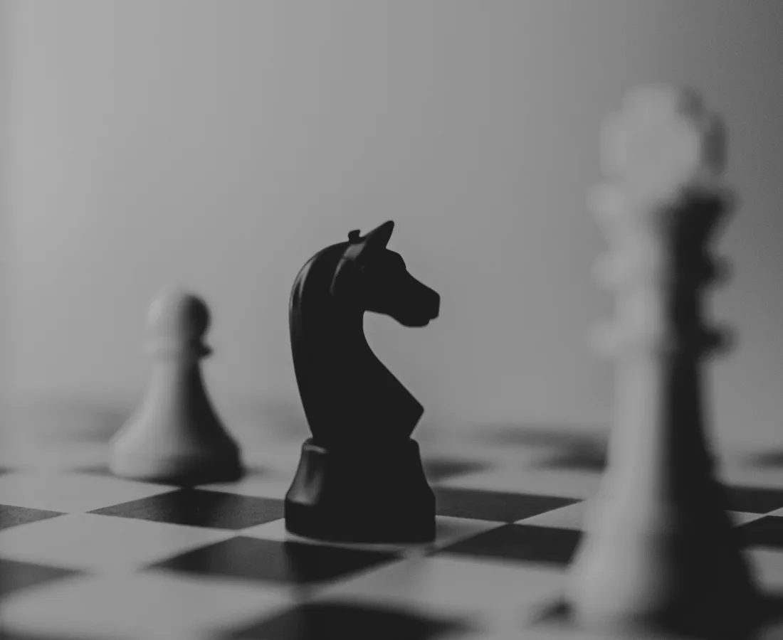 Cavalier noir au premier plan sur un échiquier, autres pièces en arrière-plan
