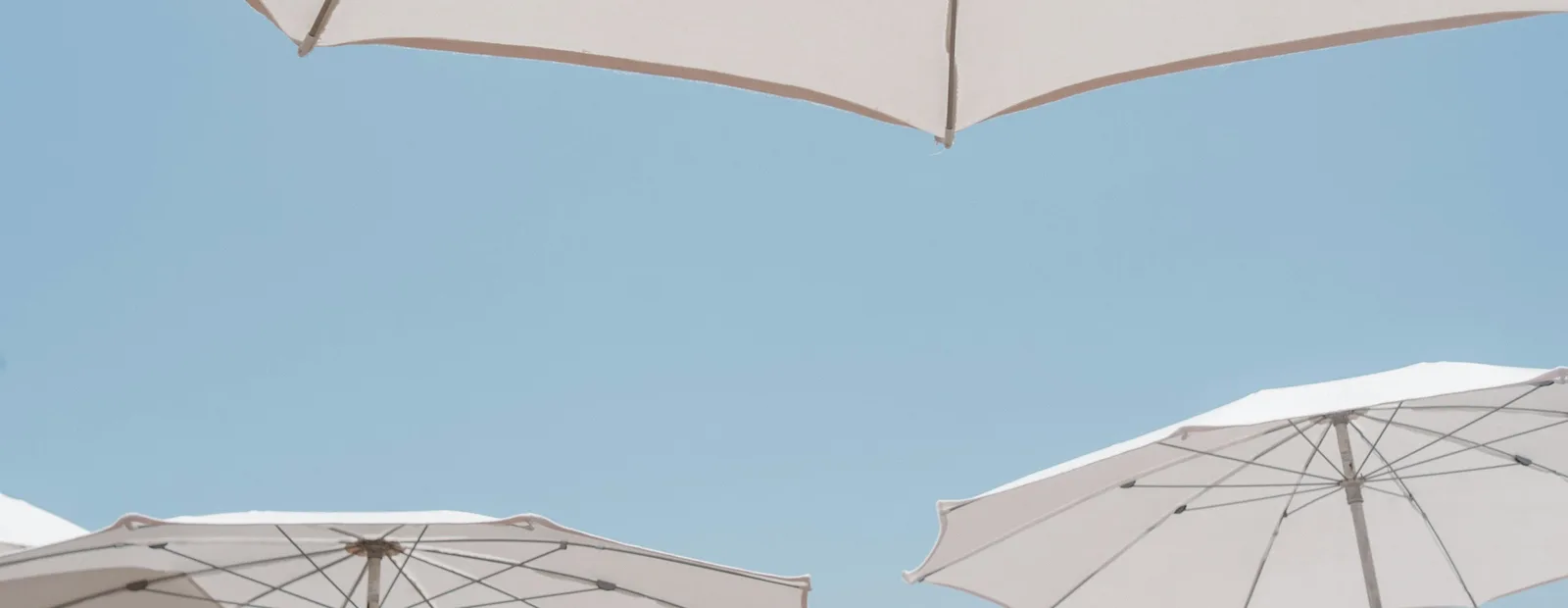 Parasols blancs déployés sous un ciel bleu uni