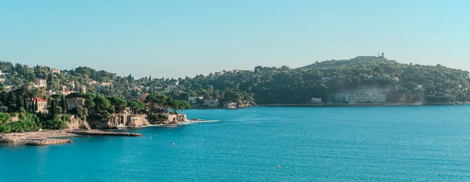 Les eaux turquoise de la rade de Villefranche-sur-Mer et sa côte boisée ponctuée de villas, sur la Côte d’Azur près de Nice.