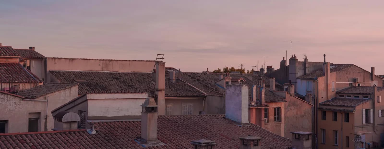 Toits de tuiles du centre ancien d’Aix-en-Provence au crépuscule, sous un ciel en dégradé du bleu au mauve.